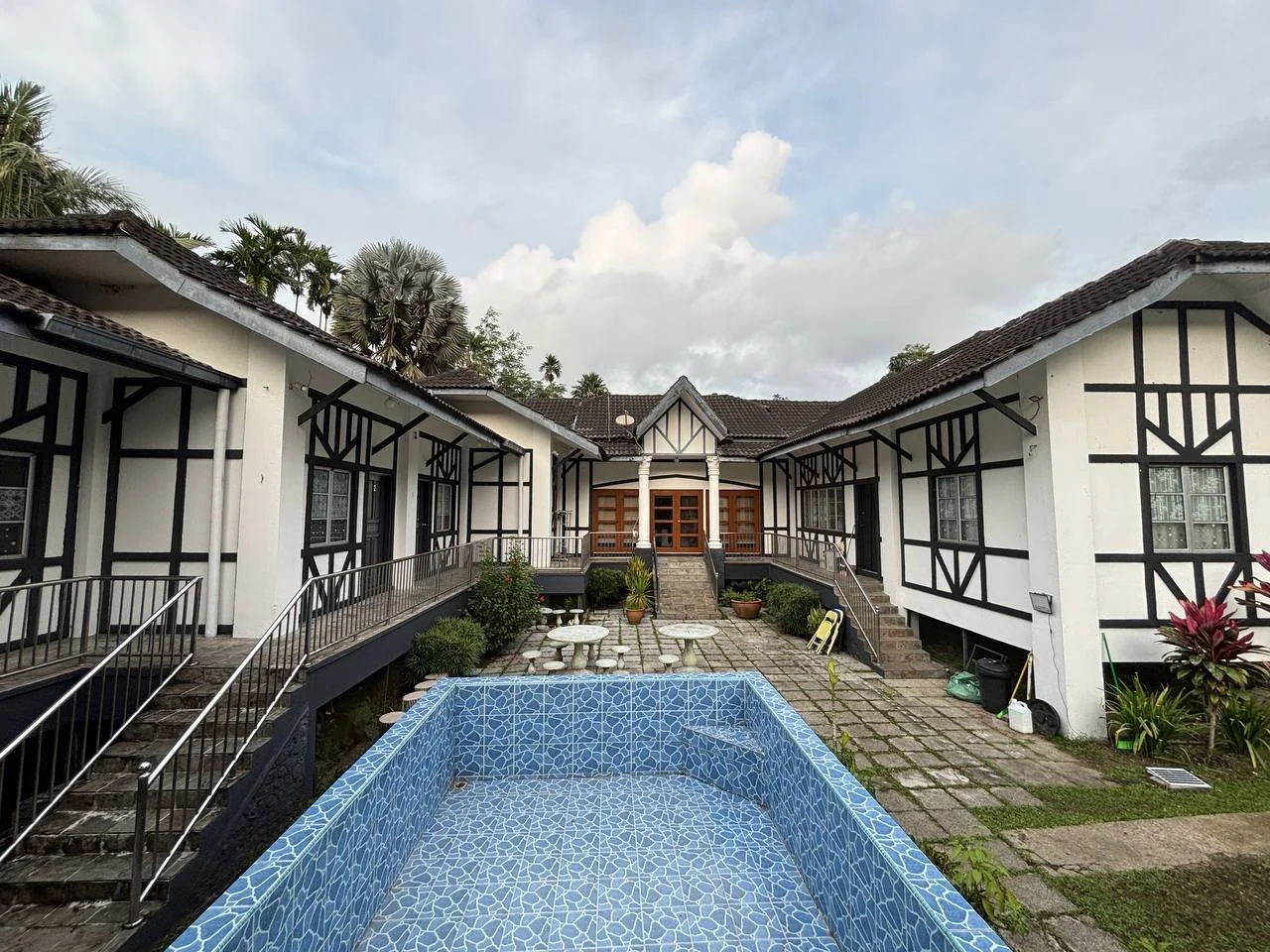 Courtyard swimming pool framed by the Tudor Bungalow's black-and-white wings